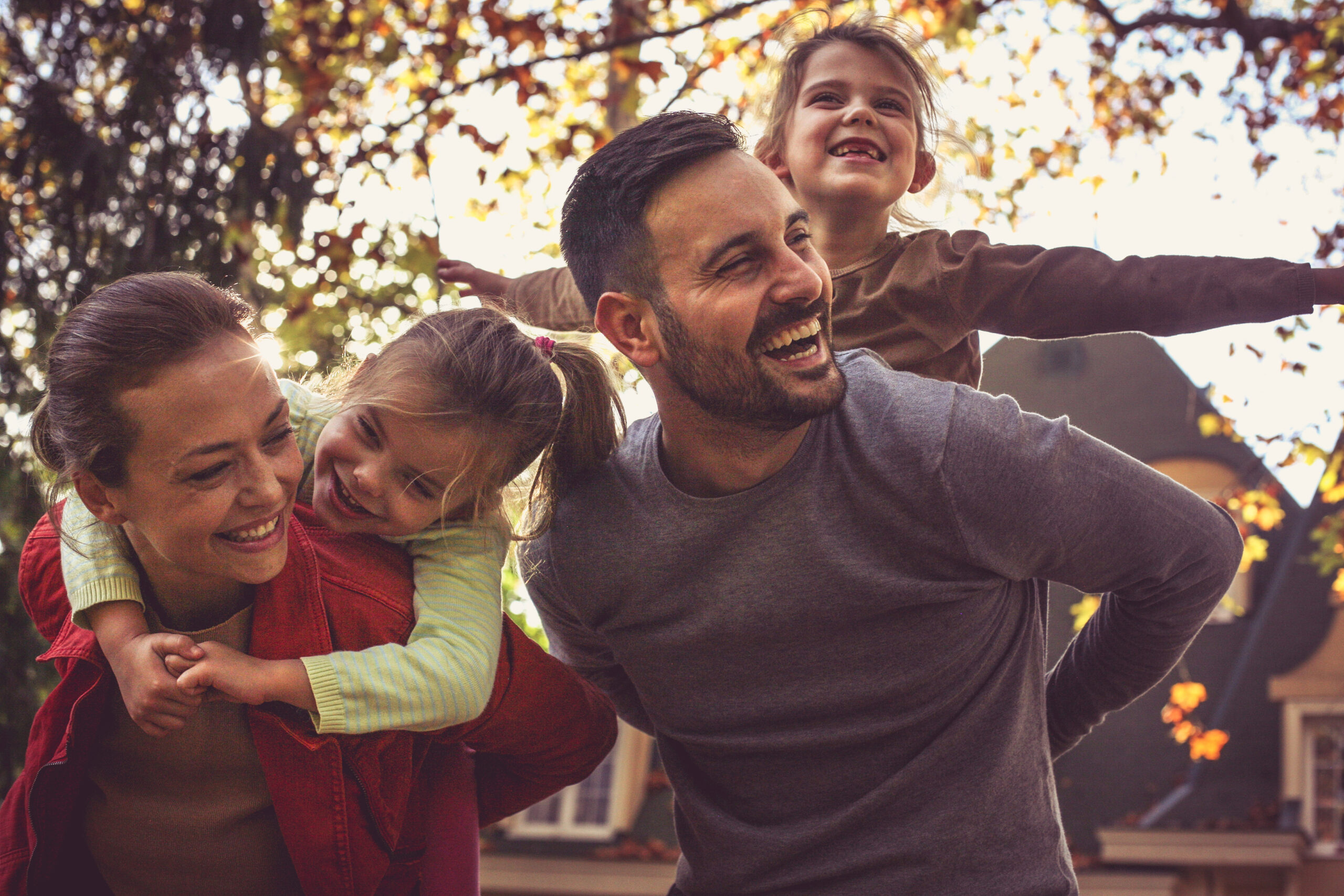 Parents,Carrying,Little,Girls,On,Piggyback.
