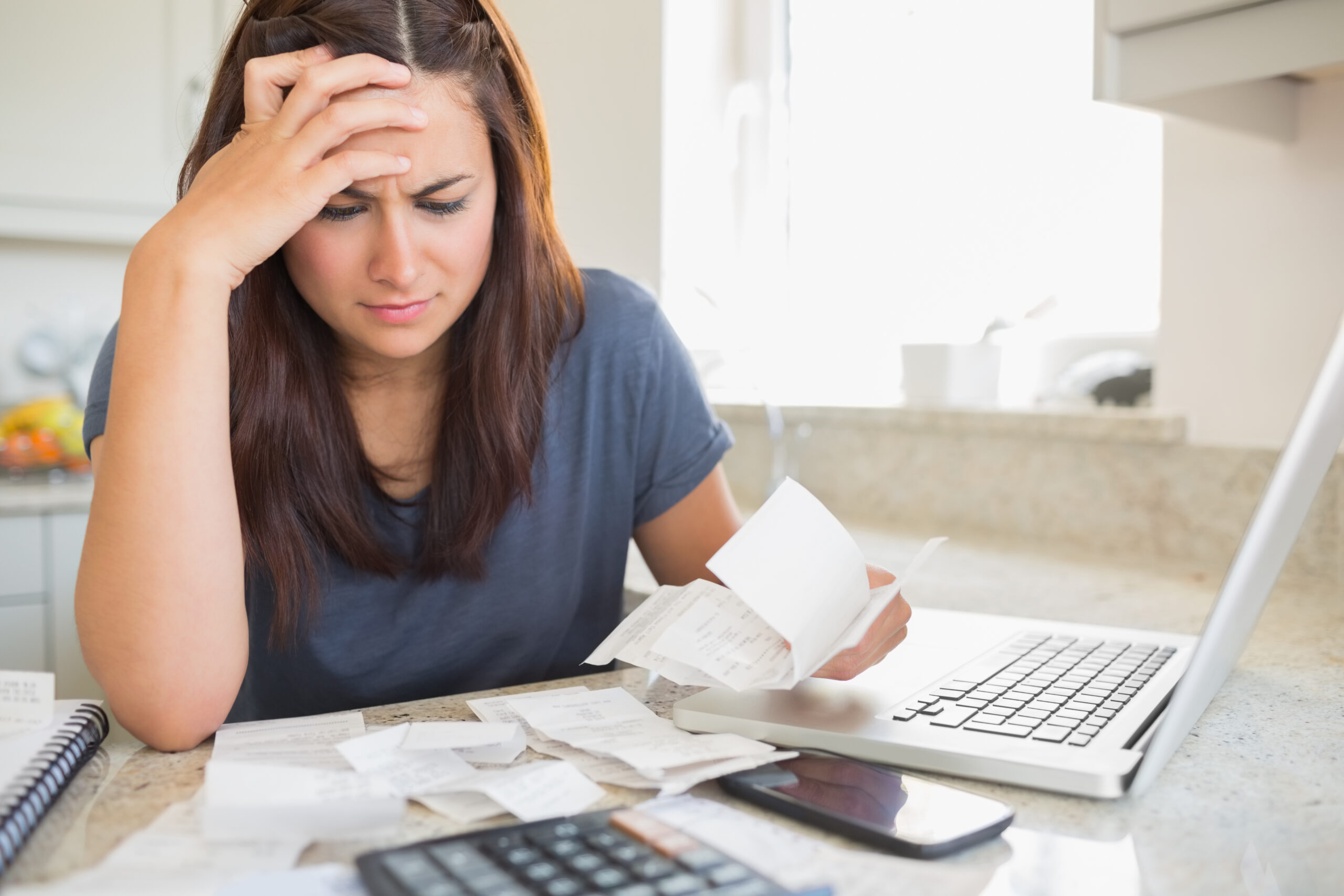 cost of health insurance, Brunette,Looking,Worried,Over,Bills,In,Kitchen.,Working,From,Home