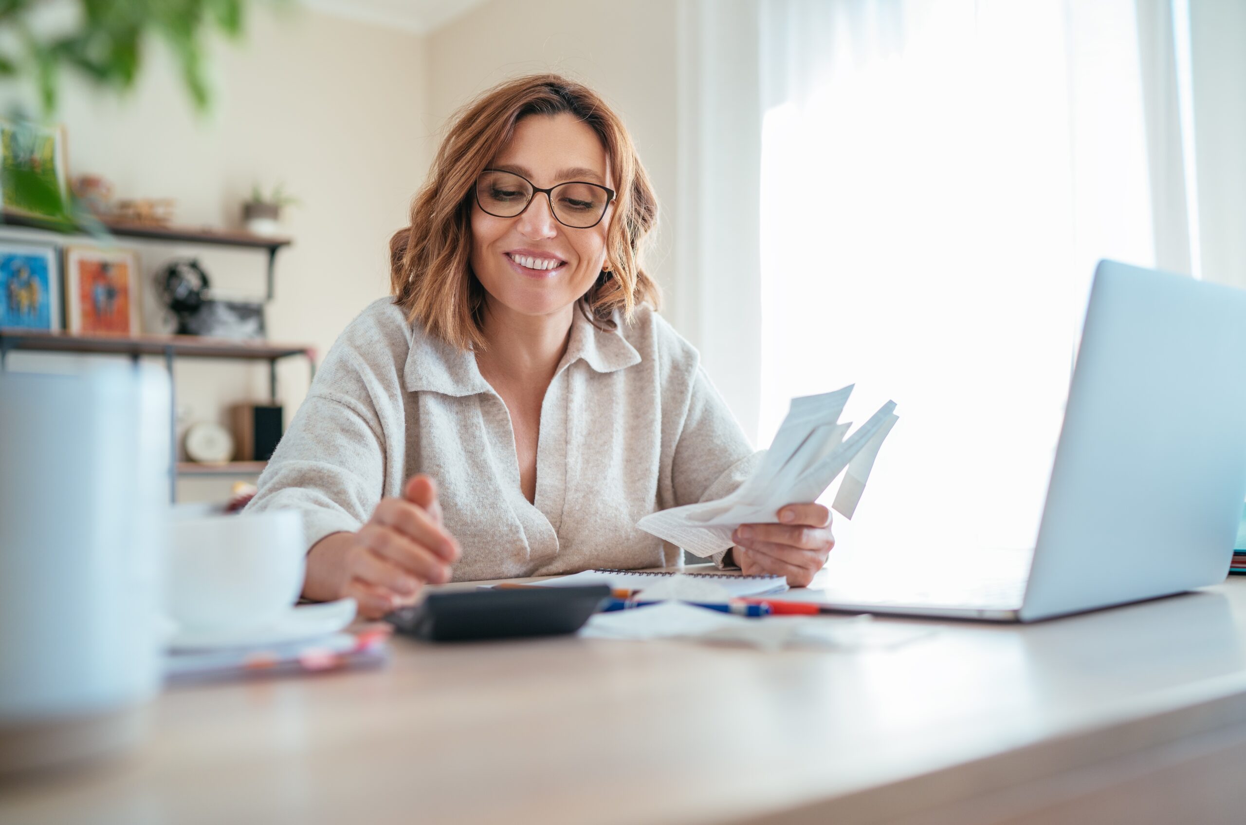 Beautiful,Middle-aged,Woman,In,Glasses,And,Paper,Bills,Joyfully,Laughing
